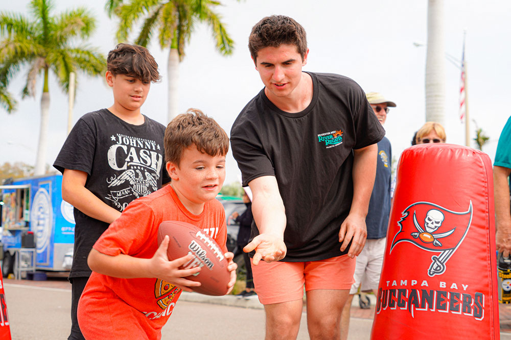 a young man hands a ball to a boy who is running