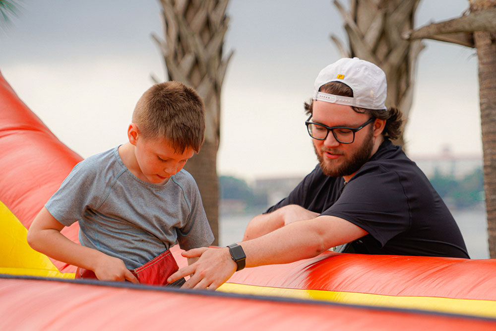 A young man helps a boy in an obstacle course.