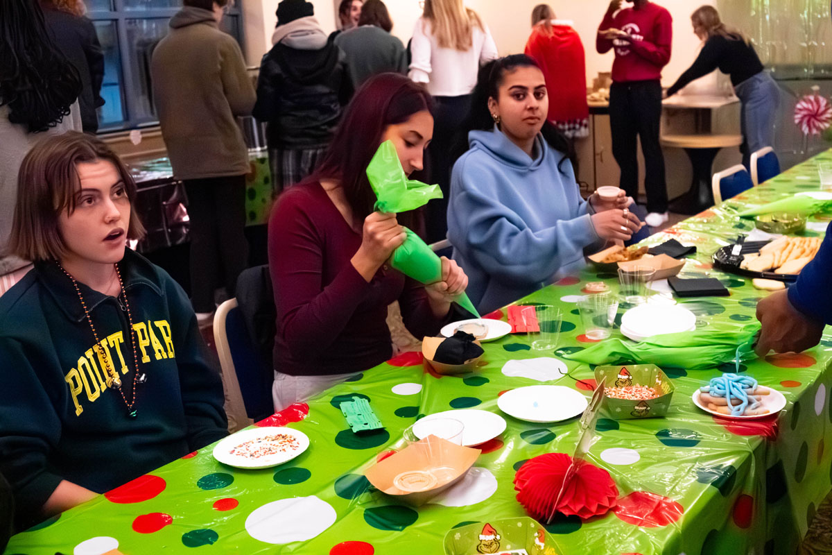 Students decorate cookies at a table.