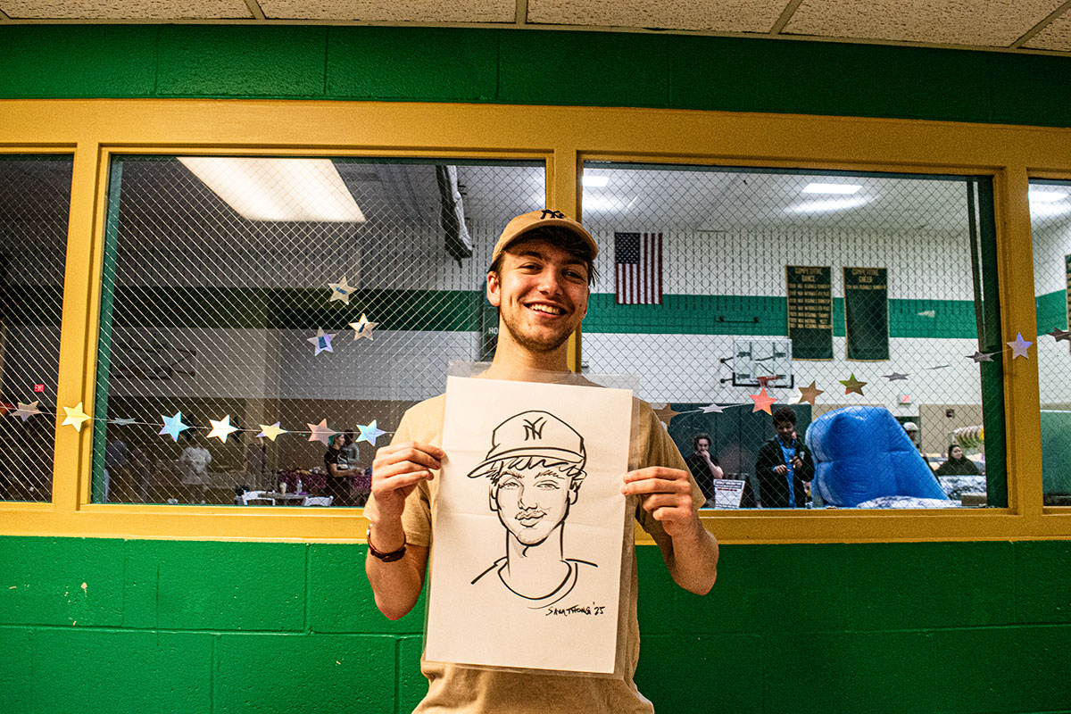 A student holds up a caricature of himself.