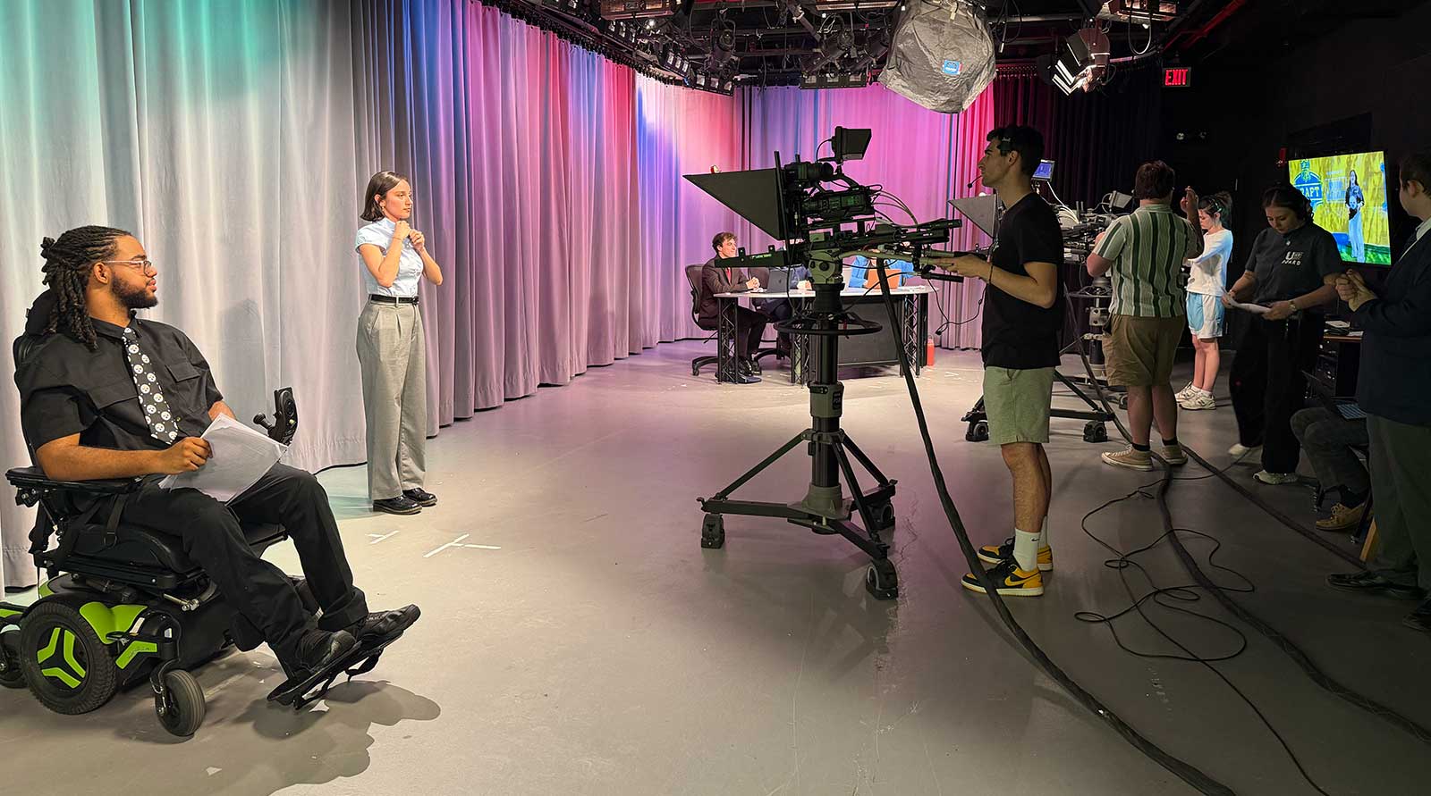 One student reports while other students man the cameras and monitors in the U-View studios.