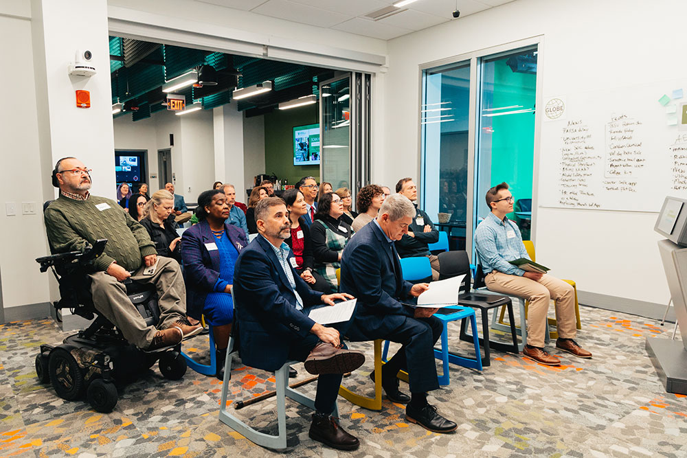 The audience listens to opening remarks.