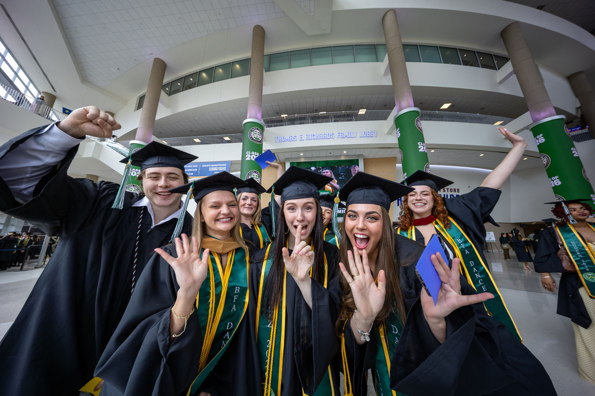 Graduates wave to the camera.