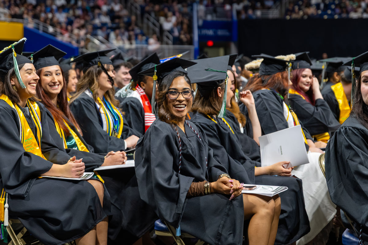 Graduates sit in their rows and smile.