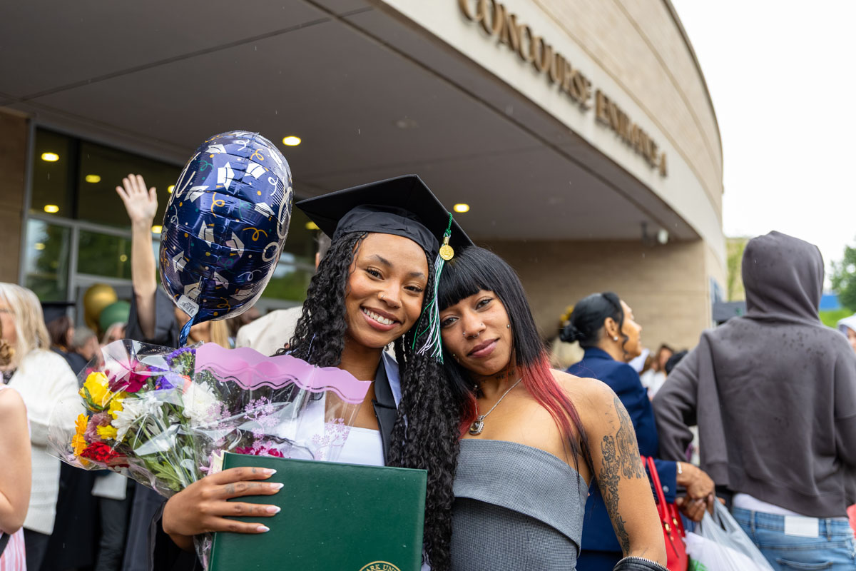 A graduate poses with a friend outside the center.