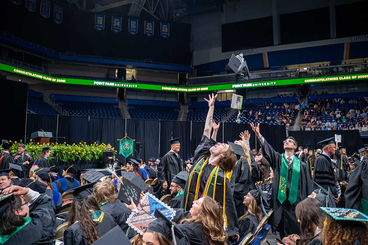 Sudents toss their caps in the air.