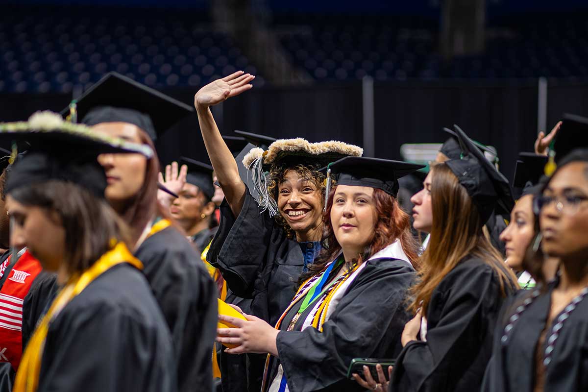 A graduate waves to family members.