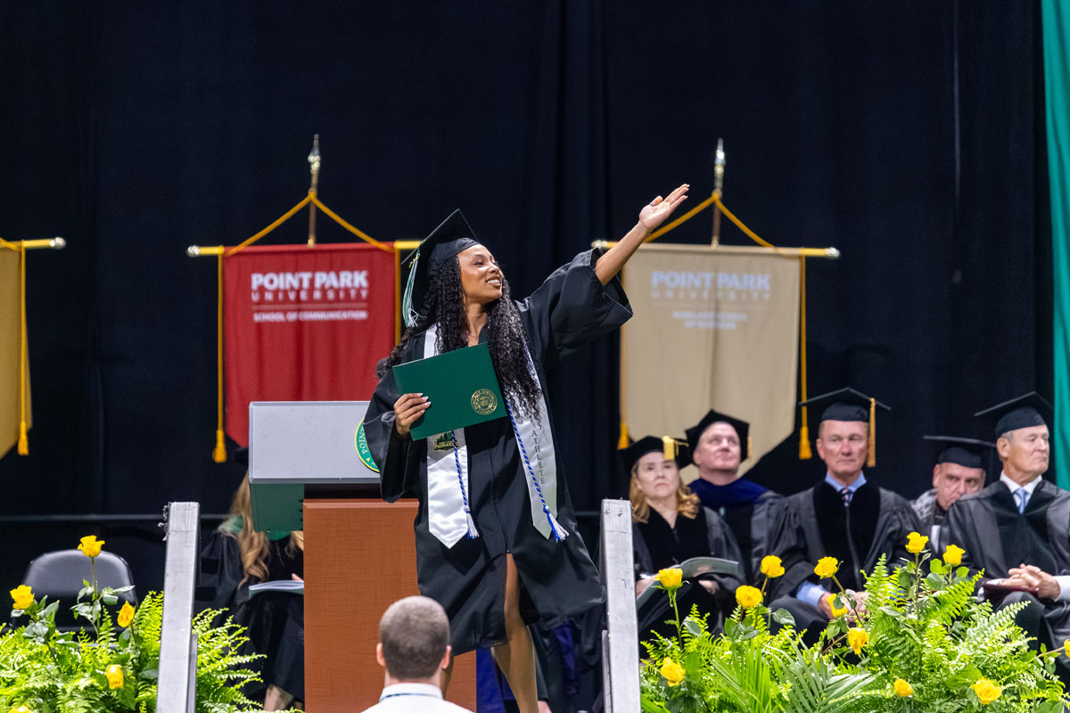 A graduate holds up their hand in the air.