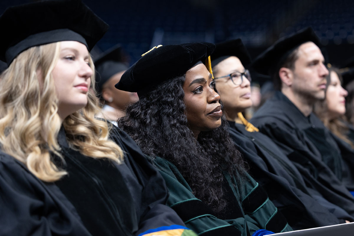 Graduates listen to the speaker in their row.