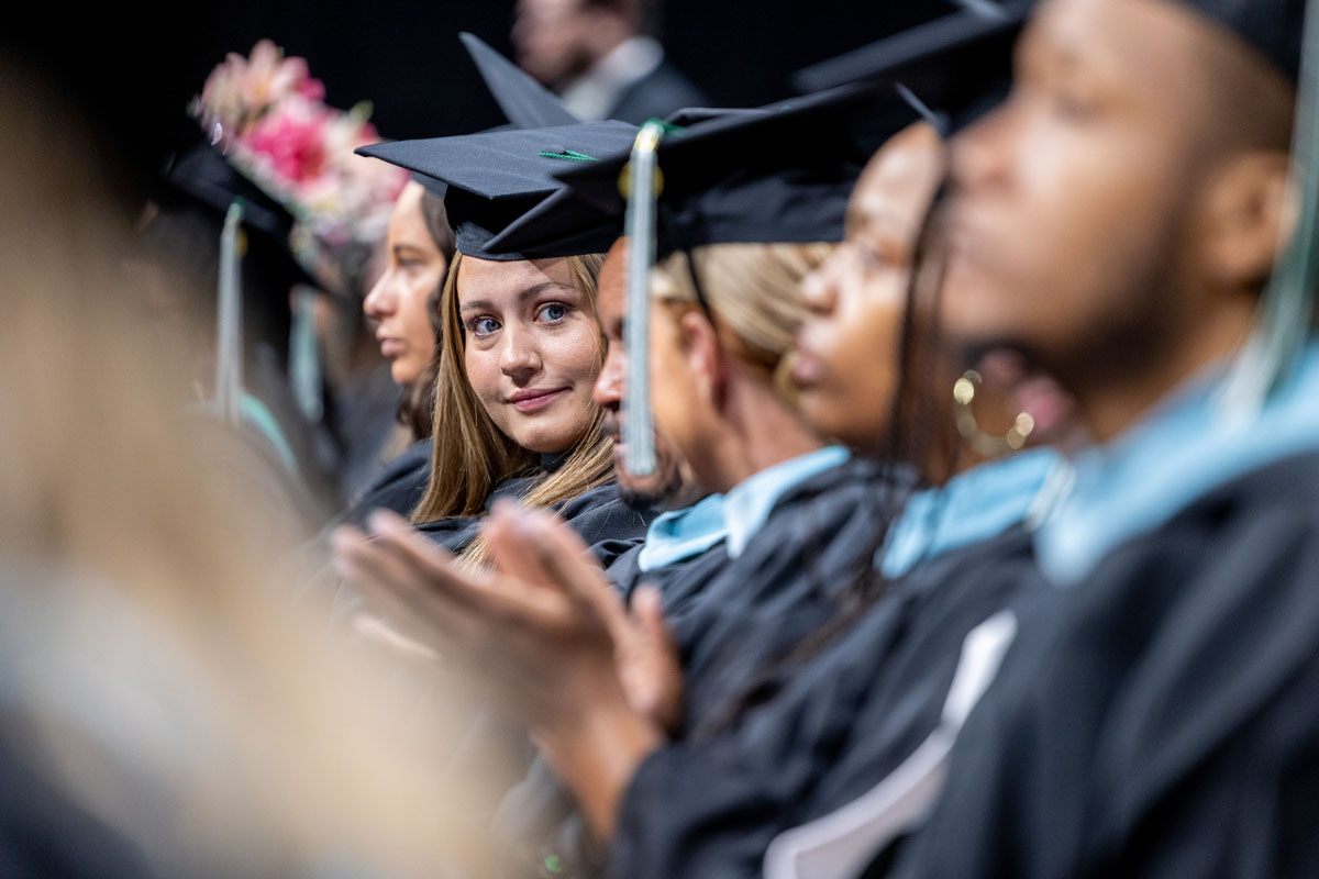 Graduates in a row smile at the camera.