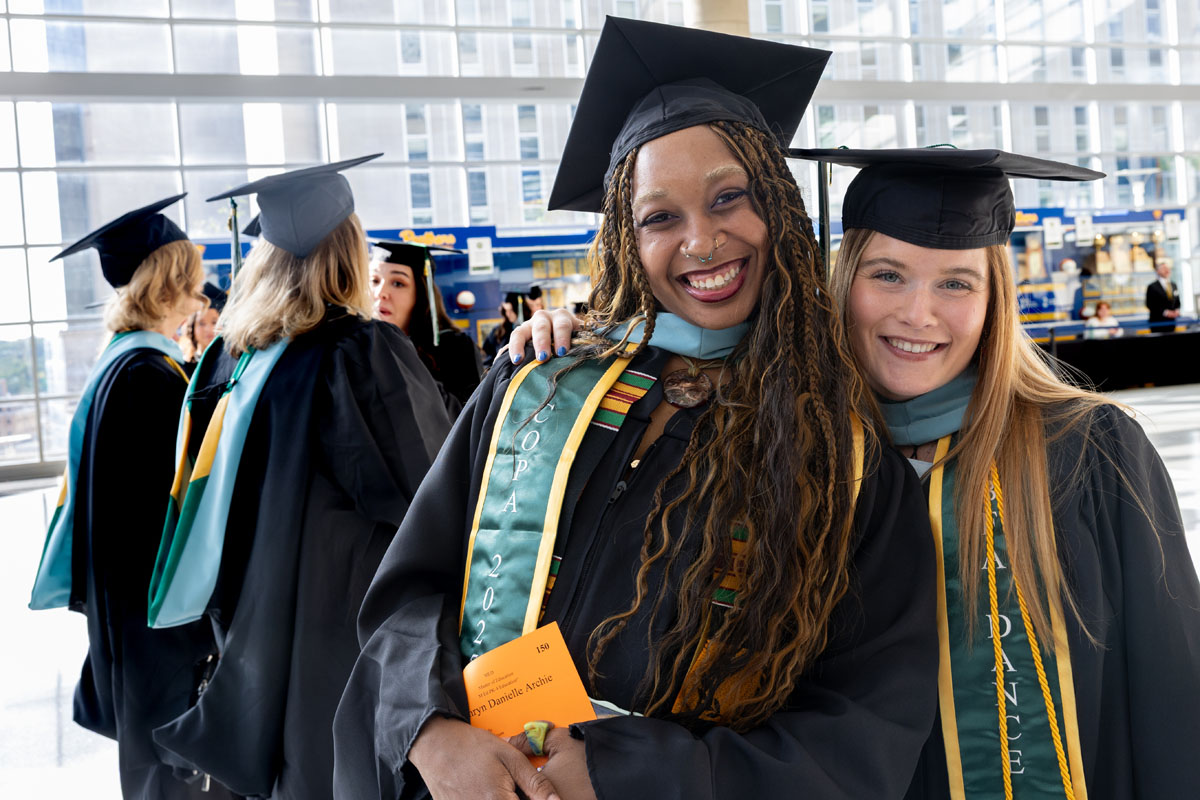 Two graduates pose for a photo.