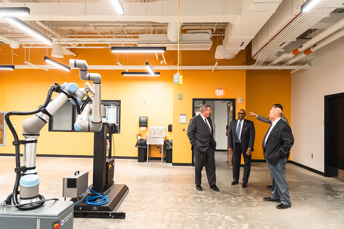 Four men stand in a room with technical equipment.