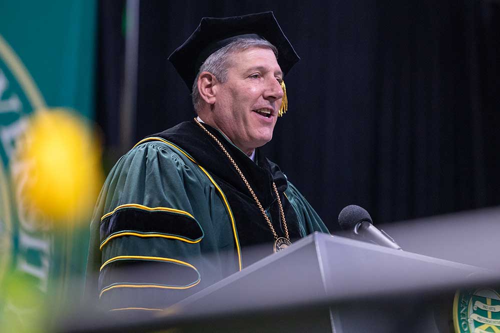 Chris Brussalis speaks from a podium.