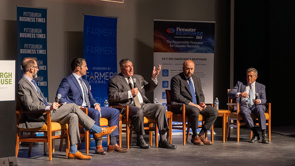 Five men are seated on the stage of the Pittsburgh Playhouse. Chris Brussalis, center, speaks. 