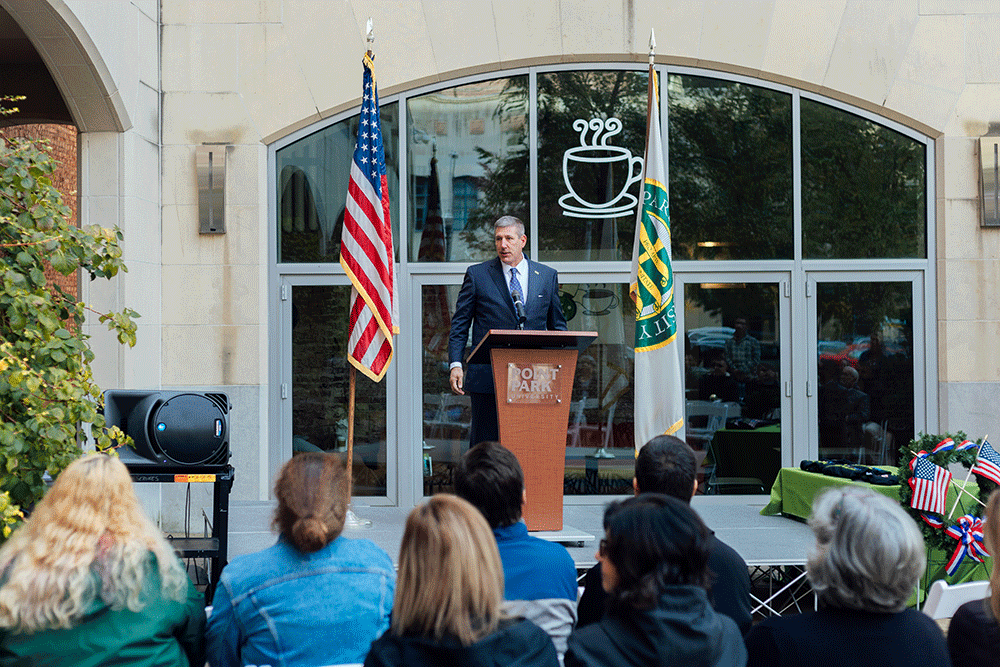 Dr. Chris W. Brussalis behind a podium addresses a crowd