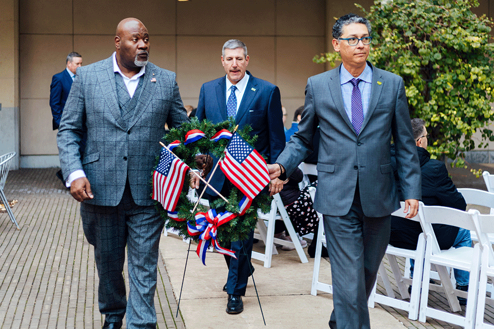 Jake Wheatley and Michael Soto carry a wreath decorated with flags