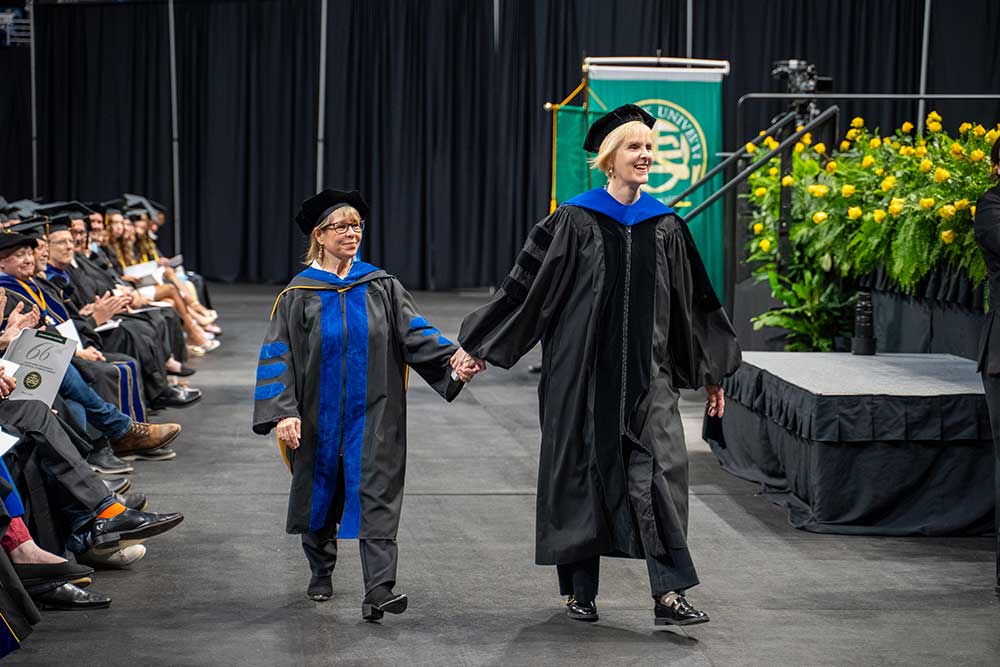 Laura Frost and Christal Edmunds walk towards the stage, holding hands.