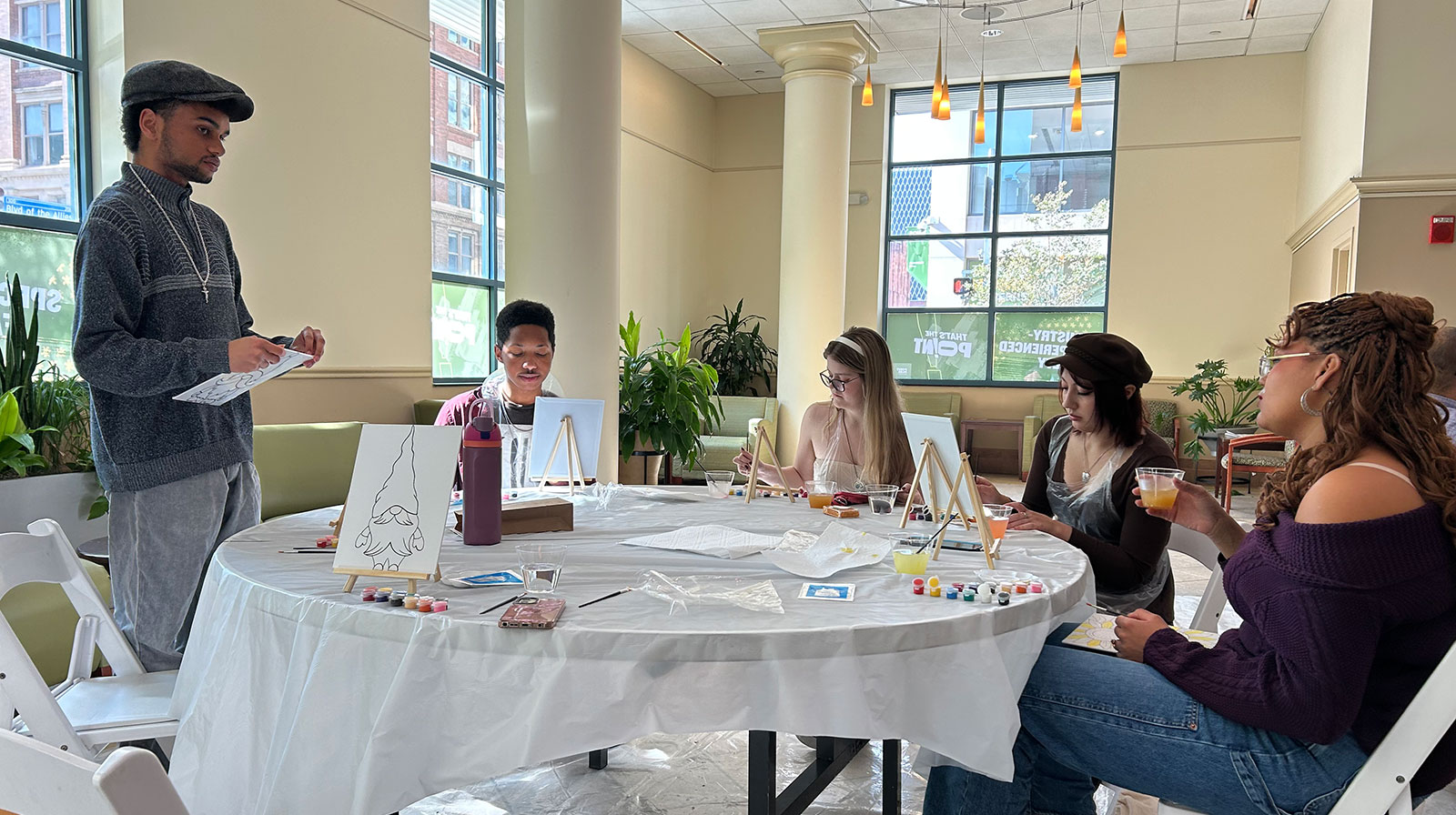 Students sit at a table painting canvases in Lawrence Hall.
