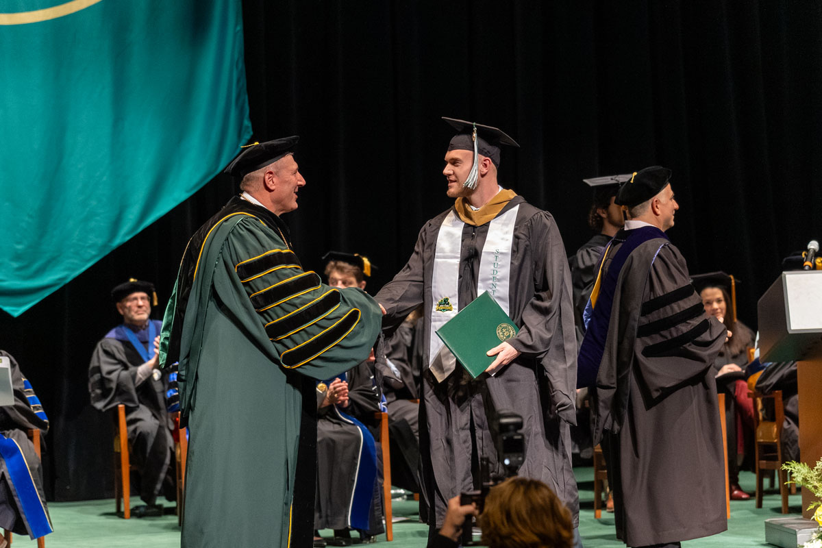 A student shakes Dr. Brussalis hand at the December hooding.