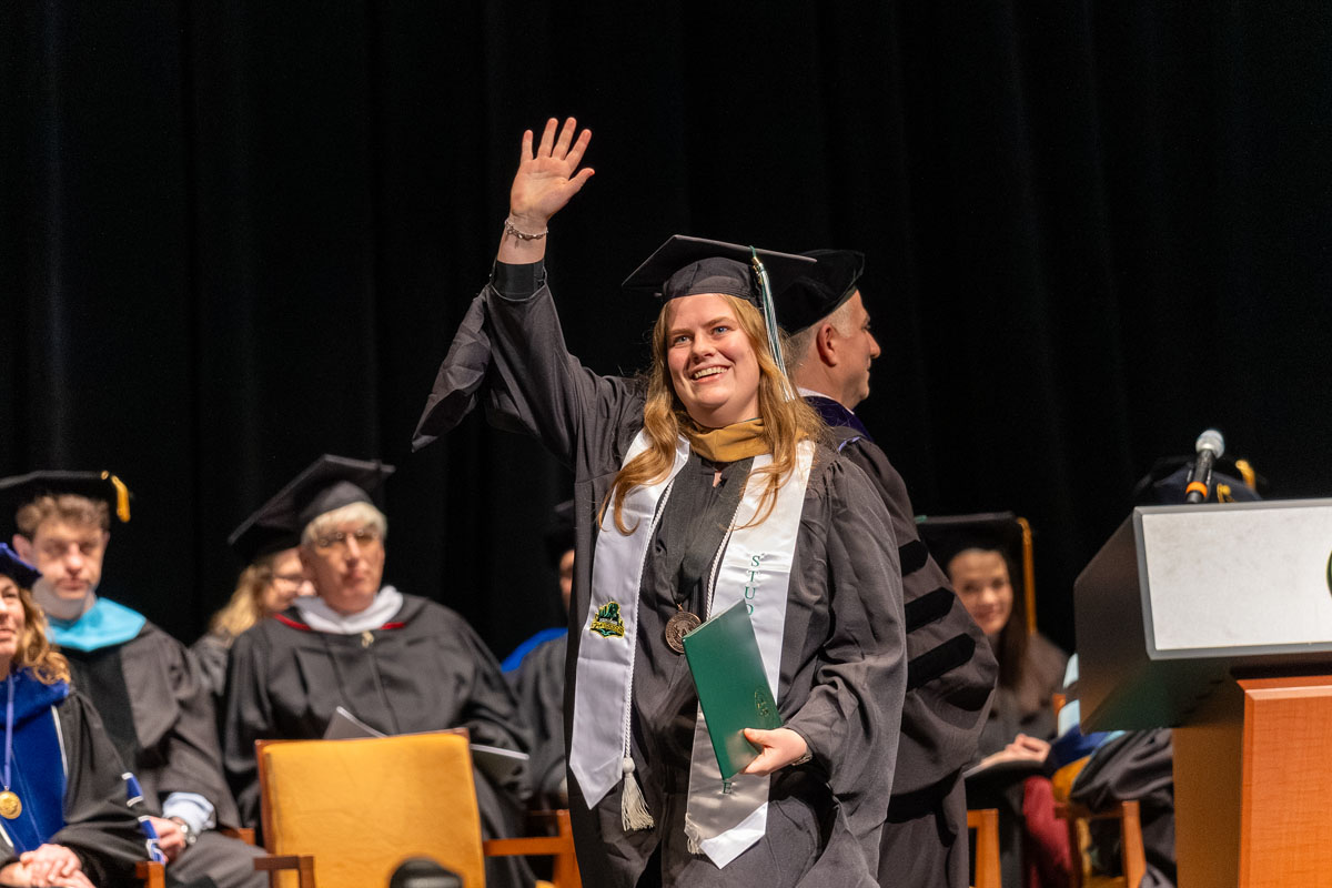 A graduate waves from the stage.