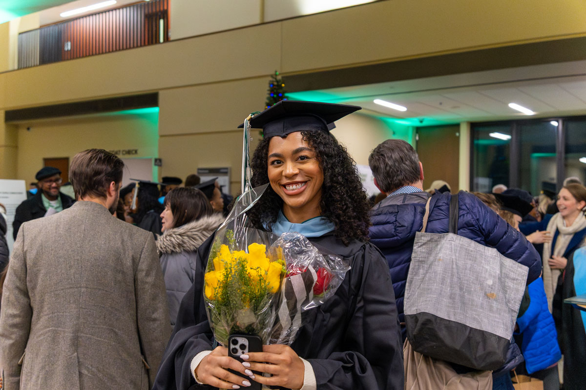 A graduate poses with flowers.
