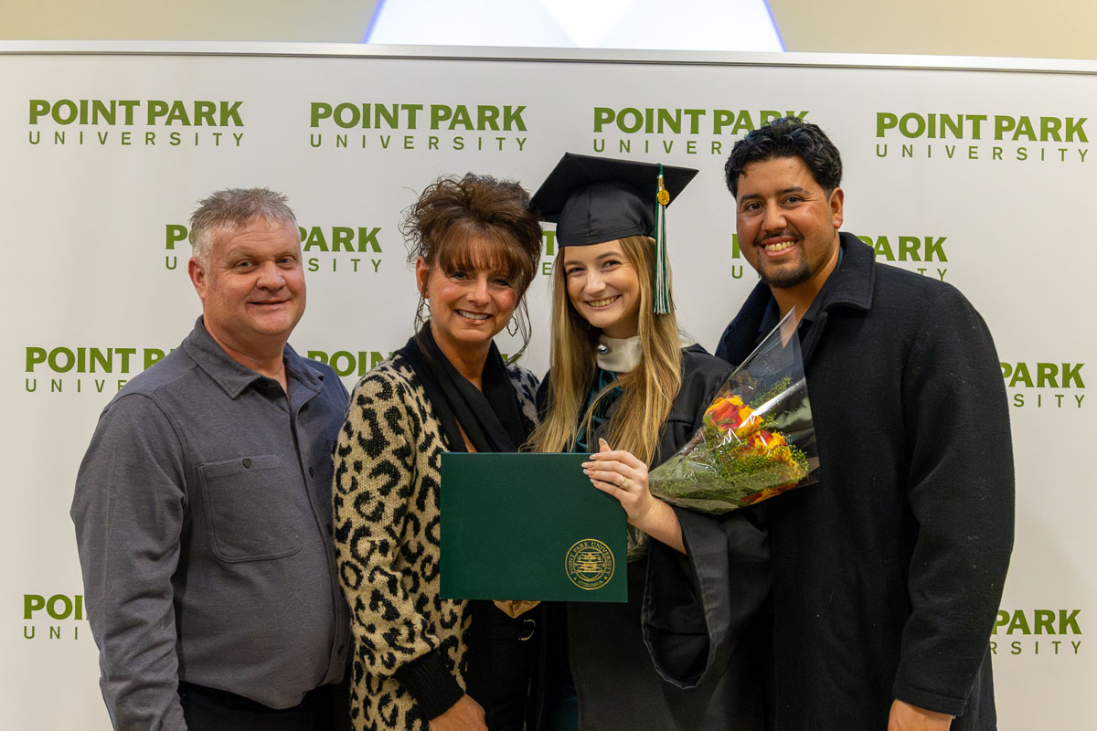 A graduate poses with her parents and husband.