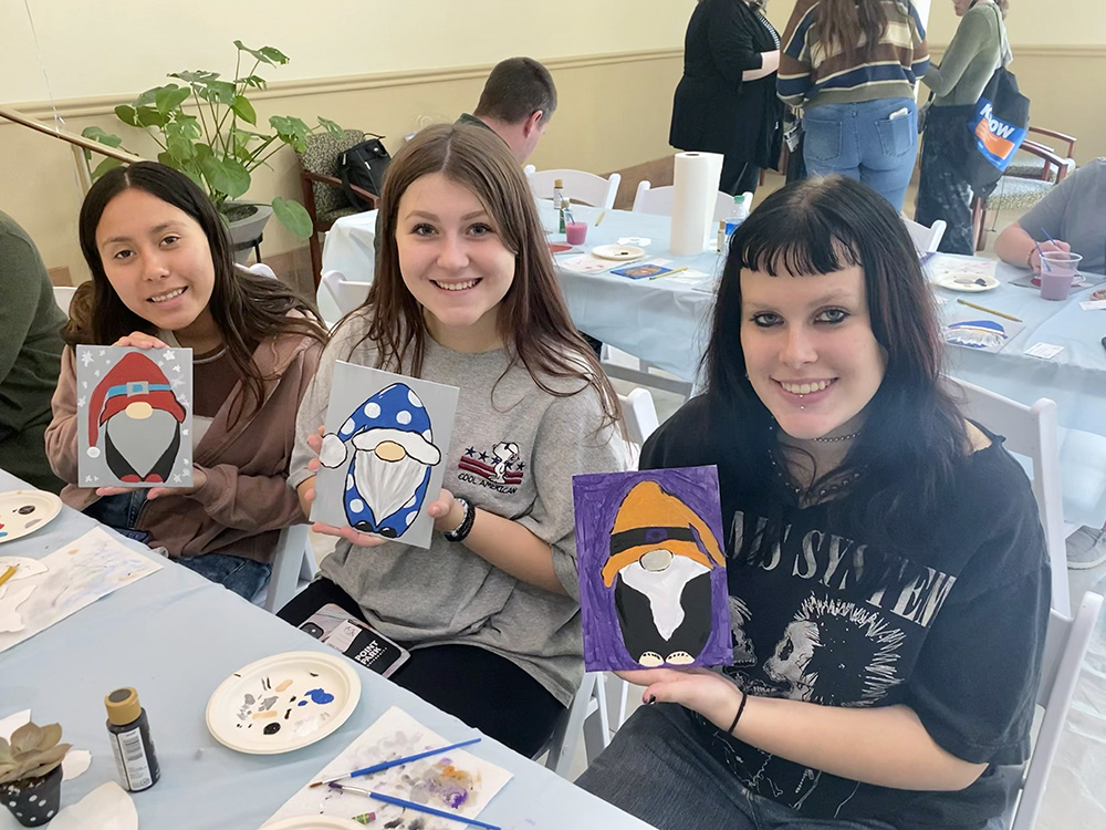 Three students pose with their gnome paintings at the Pioneer Pause. Photo by Nicole Chynoweth.