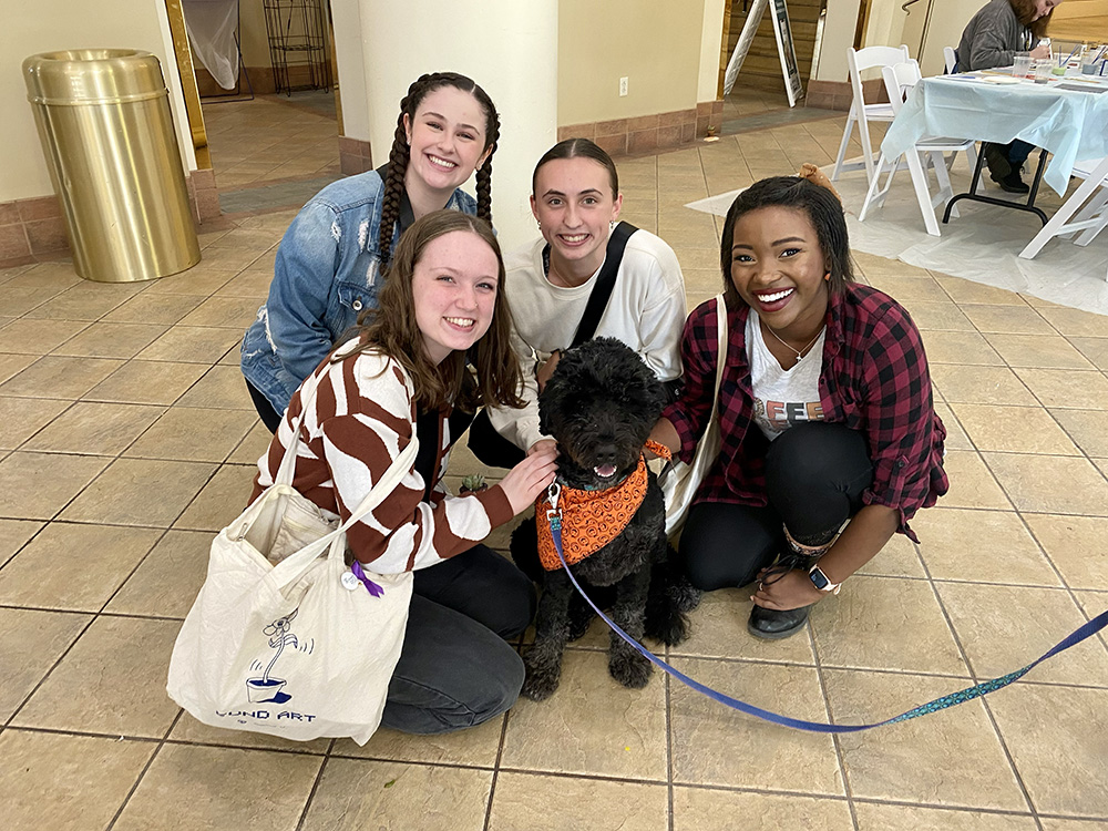 Pictured are four students with a therapy dog in Lawrence Hall. Photo by Nicole Chynoweth.