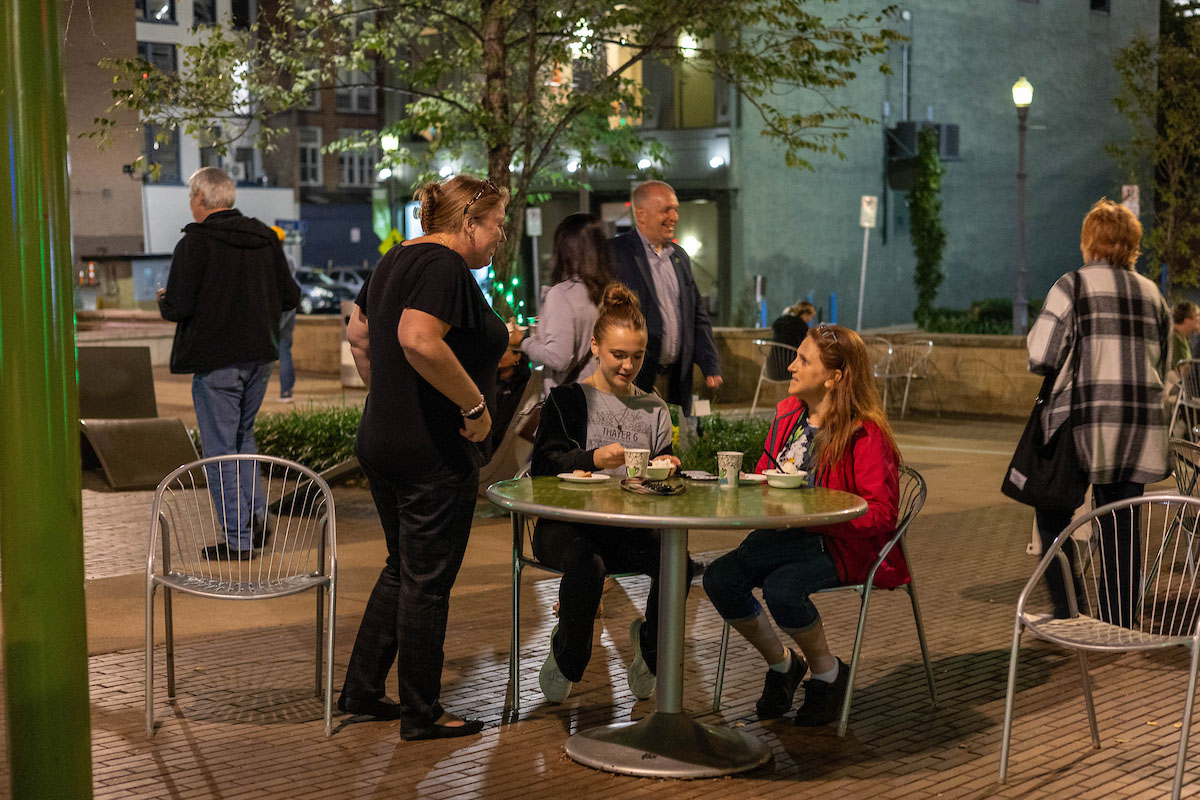 Family members talk at a table in Village Park in the evening. 
