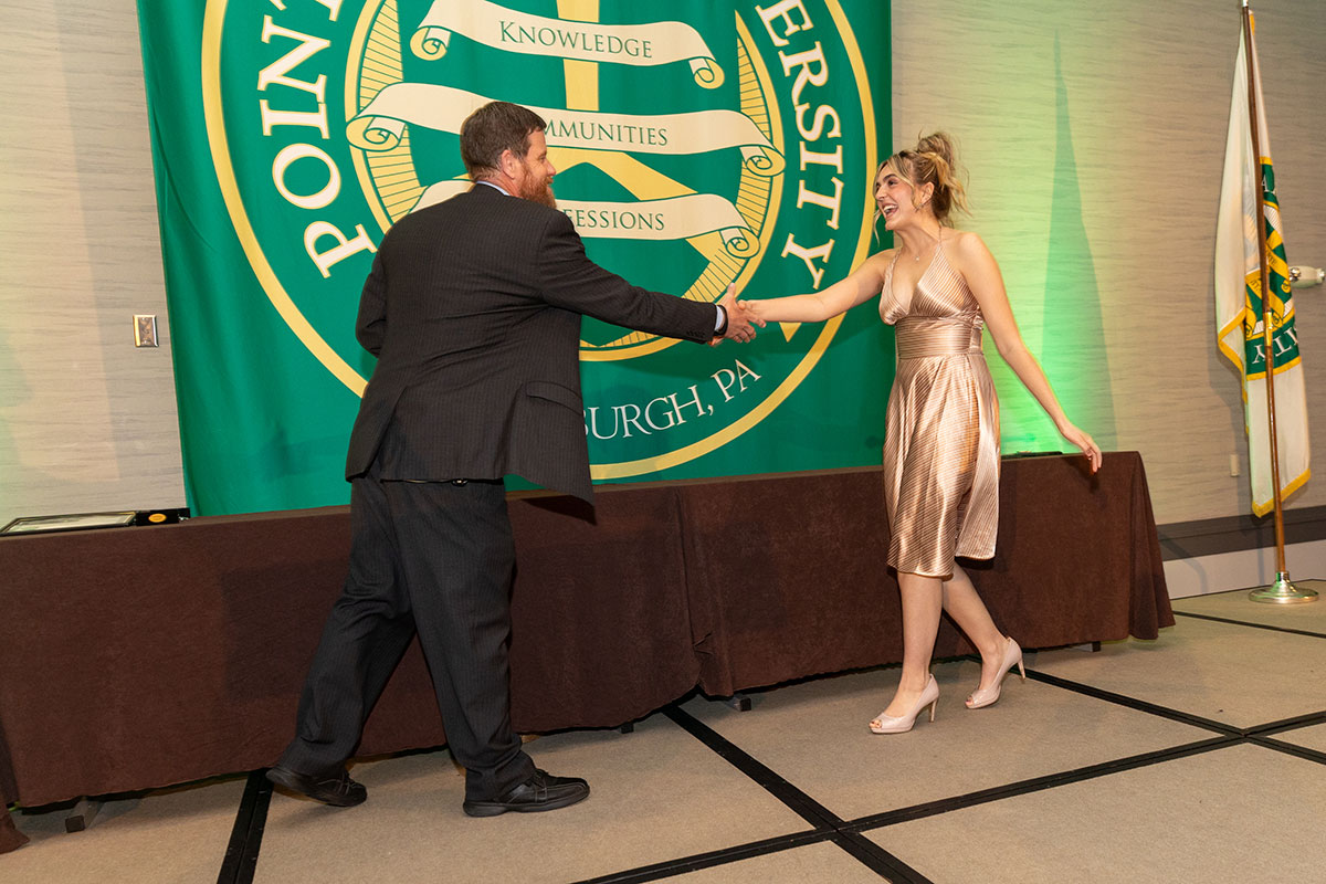A girls shakes a hand as she receives her award