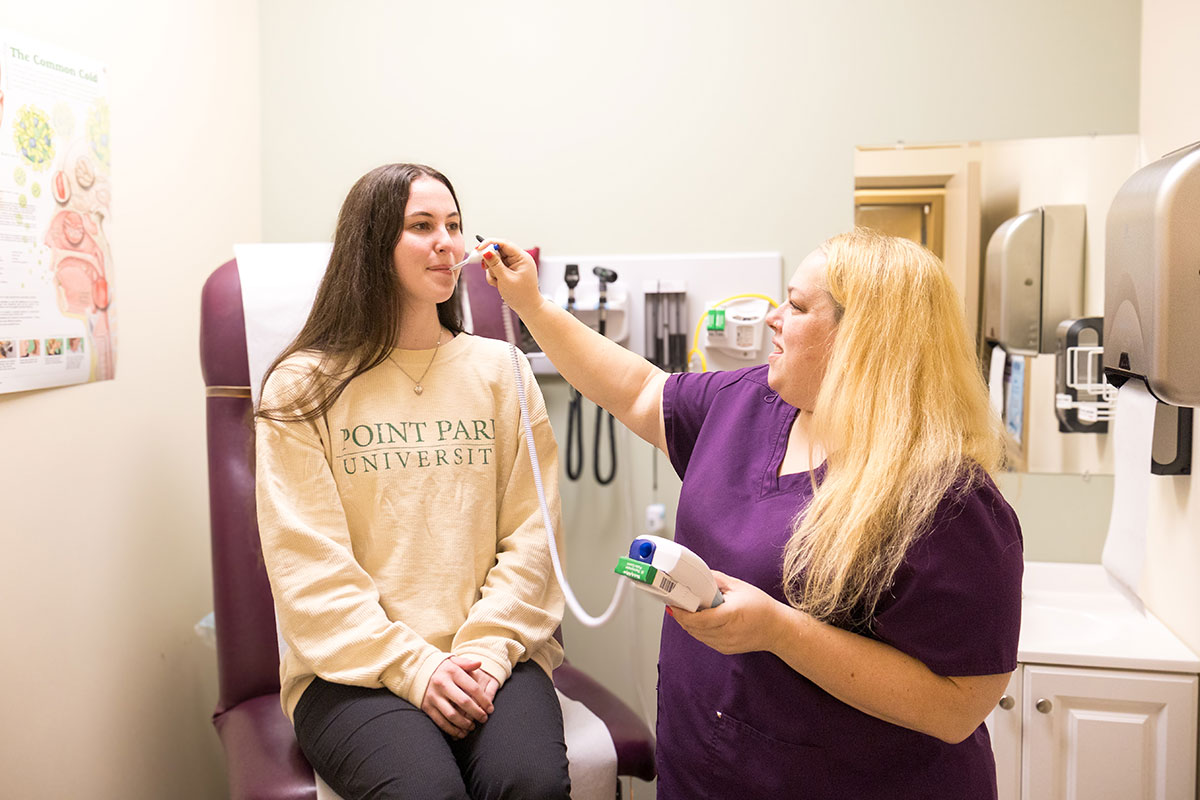 A student has their temperature taken in the student health center.