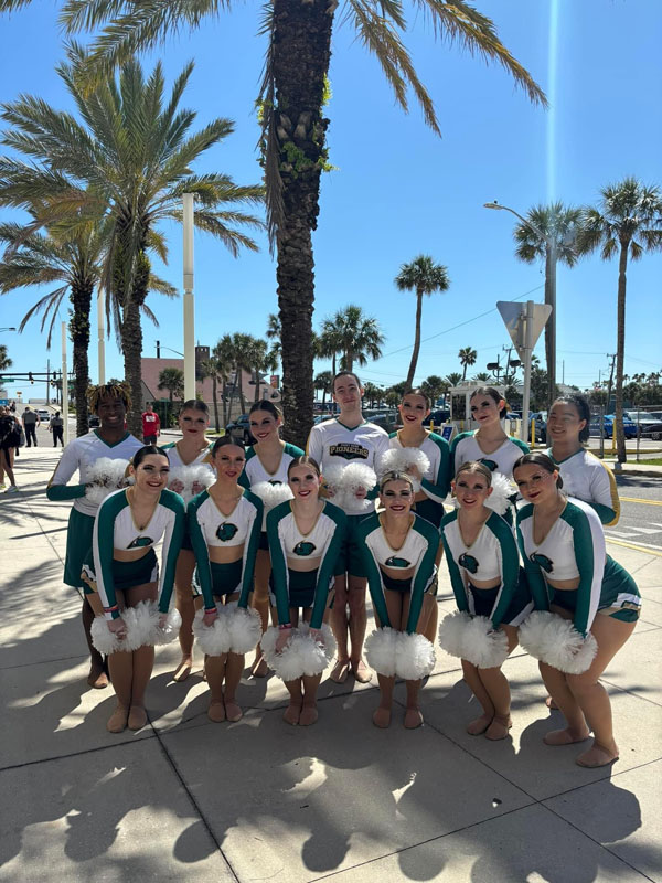 The team poses in Florida with palm trees in the background.