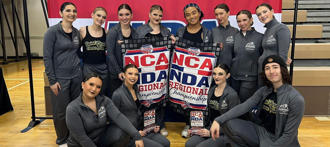 Team members pose in front of a banner.