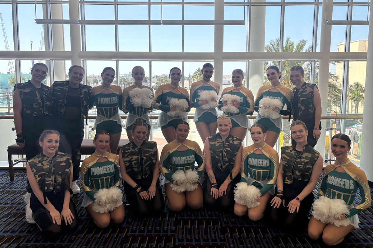 The team poses before a wall of windows.