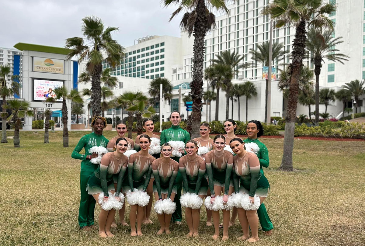 The team poses outside with palm trees in the background.