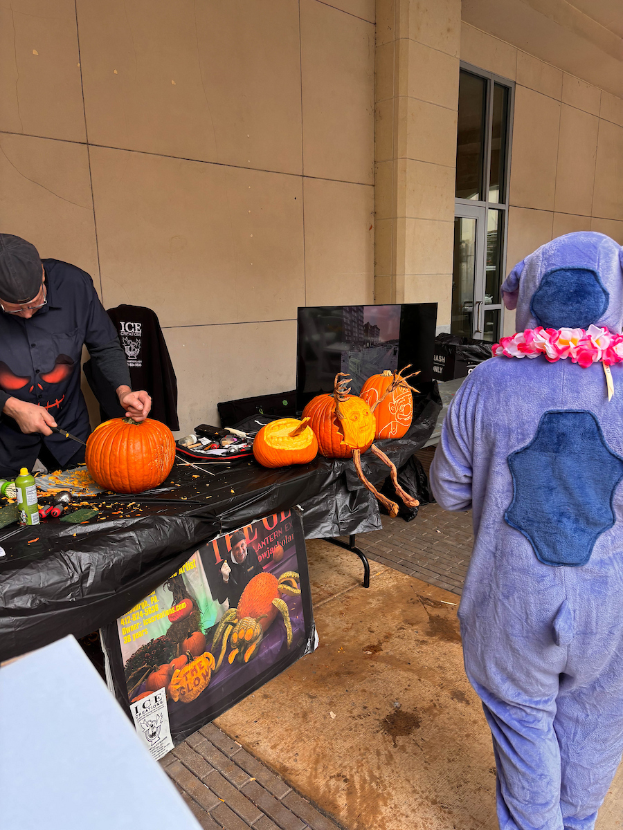 A man carves a pumpkin in Village Park.