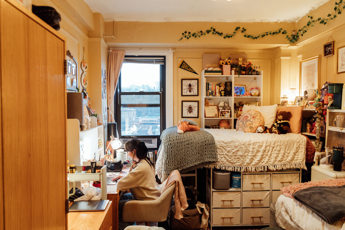 A student sits at a computer in her dorm.