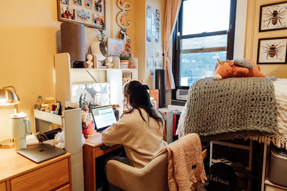 A student at a desk in a dorm.