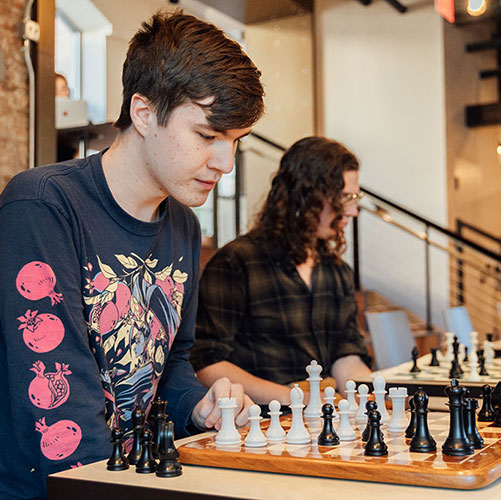 Two students play chess in the campus coffeeshop.
