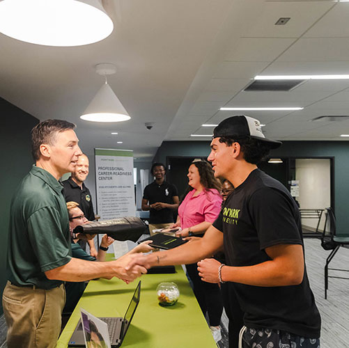 A student shakes the hand of Dean Jolin.