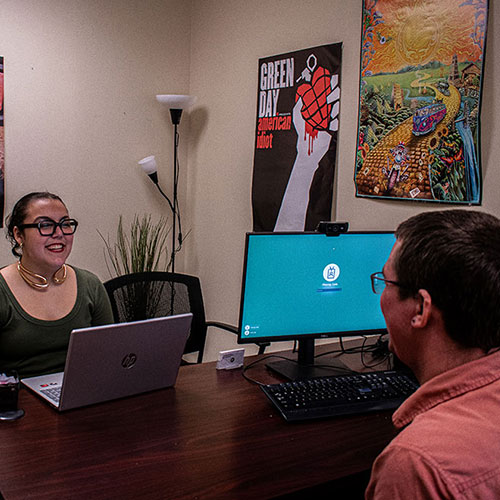 A student talks to an advisor at a desk.
