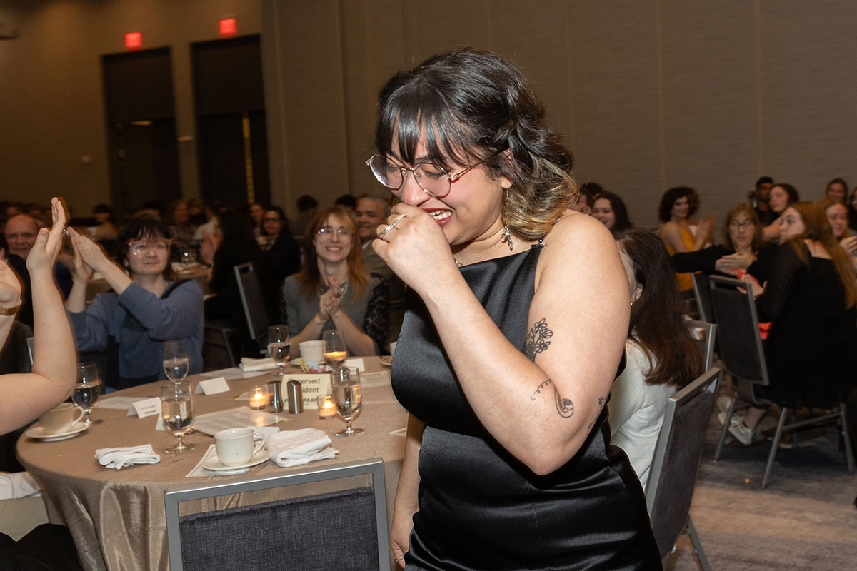 A girl covers her mouth as she smiles and walks to the stage