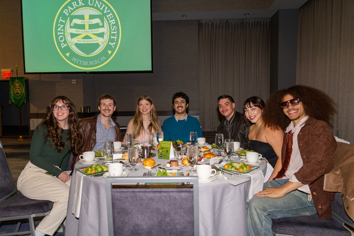 Students sit around a dinner table.