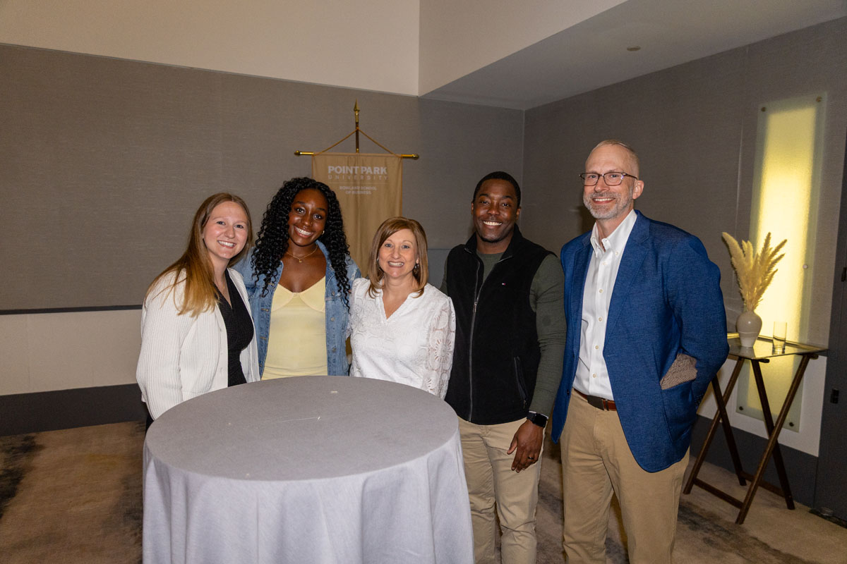 People smile for the photo standing around a table.